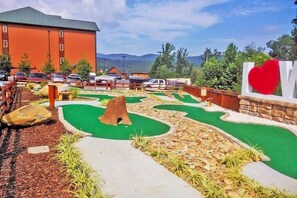 Play a round of mini-golf amidst a unique course design featuring a central tree hole and heart-shaped green.