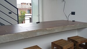 Un espace de vie moderne comprenant un comptoir de cuisine, des tabourets en bois, un téléviseur fixé au mur et un escalier menant à un espace extérieur.