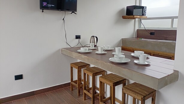 Une cuisine moderne équipée d’un téléviseur à écran plat, de tabourets en bois, d’un coin café et offrant une vue par la fenêtre.