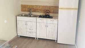 A small kitchen with a white refrigerator, a stove, and a sink. - 35 Arsena St (Tbilisi)