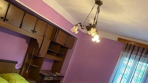 A bedroom with a bed, wooden wardrobe, radiator, and a patterned rug. - 35 Arsena St (Tbilisi)