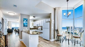 Une cuisine moderne dotée d’un îlot central, de meubles blancs et offrant une vue sur la ville.