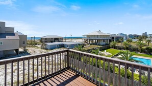 A beachfront property with a wooden deck, a swimming pool, and multiple buildings with beach access.