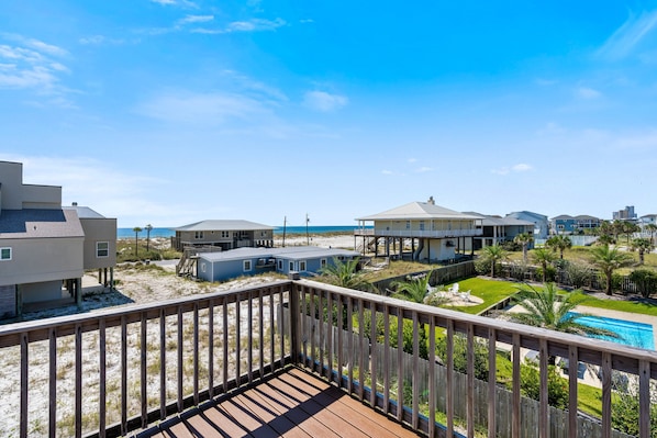 A beachfront property with a wooden deck, a swimming pool, and multiple buildings with beach access.