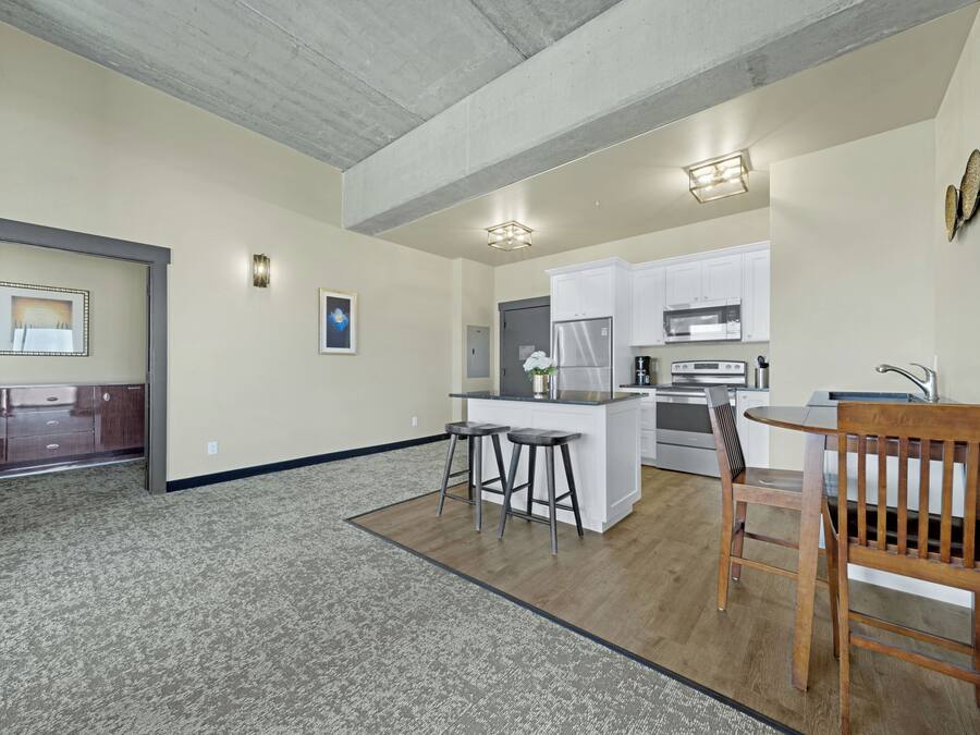 Una cocina moderna con armarios blancos, una isla central y taburetes de bar.