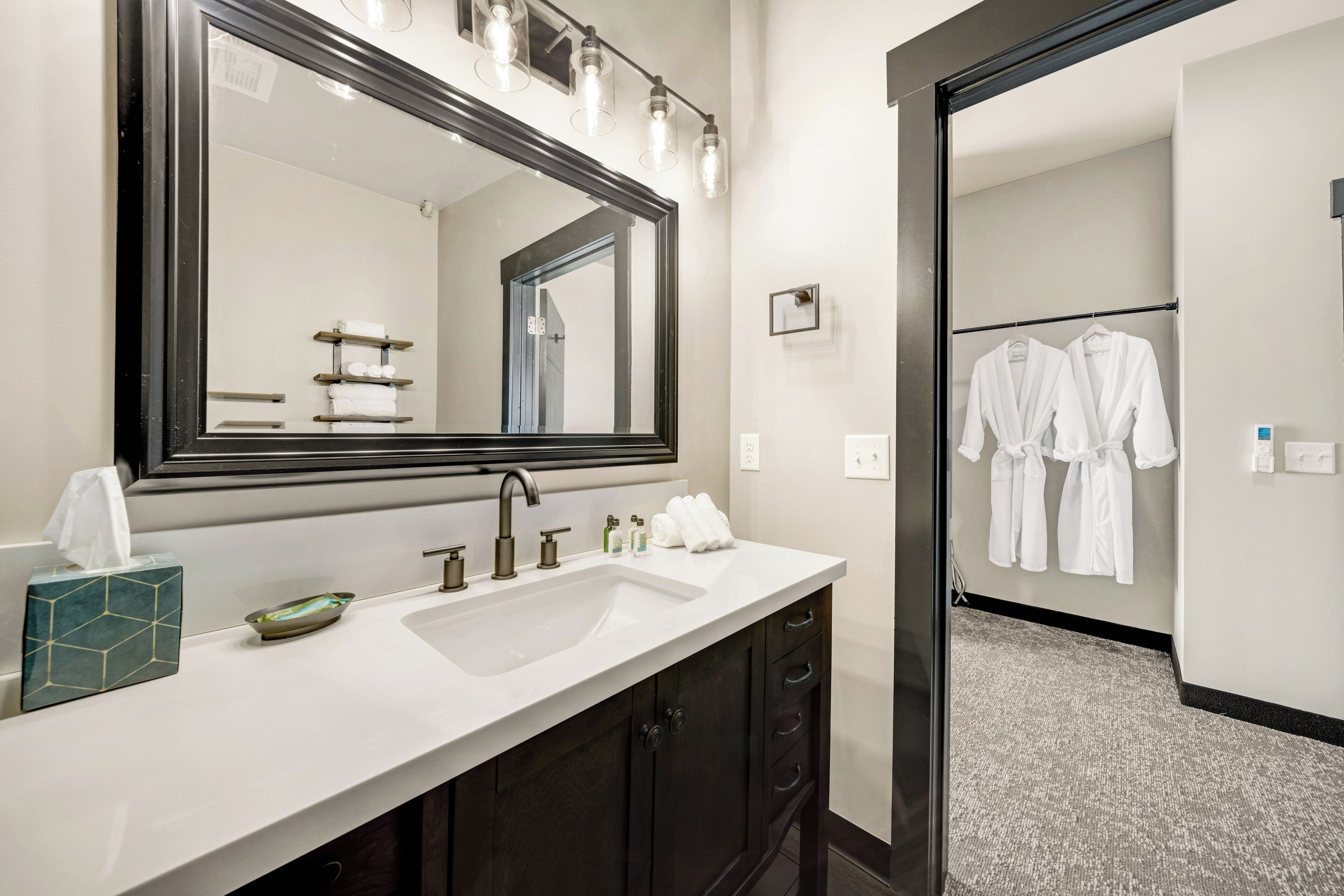 A hotel bathroom with a large mirror, a sink, and a towel rack.
