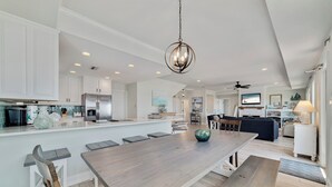 Una cocina amplia con una isla grande, armarios blancos y electrodomésticos modernos.