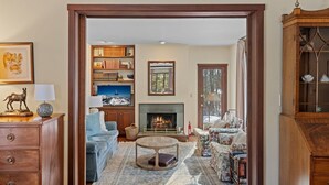 A cozy living room with a fireplace, a television, and a bookshelf. - RMR: Lake Creek Cottage Home in The Aspens (Wilson)