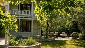 A two-story house with a covered patio area, stone retaining walls, and outdoor furniture. - RMR: Lake Creek Cottage Home in The Aspens (Wilson)