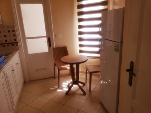 Een koelkast, een oven, een kookplaat, kookgerei, borden en bestek