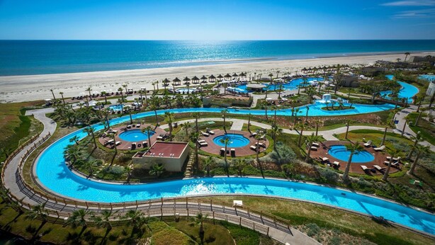 Un resort con varias piscinas, playa y vista al océano.