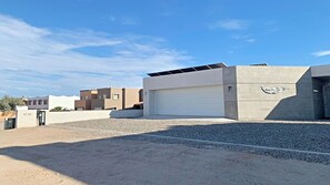 Un bâtiment moderne doté d’un grand portail de garage, d’un panneau solaire sur le toit et d’une façade en béton.