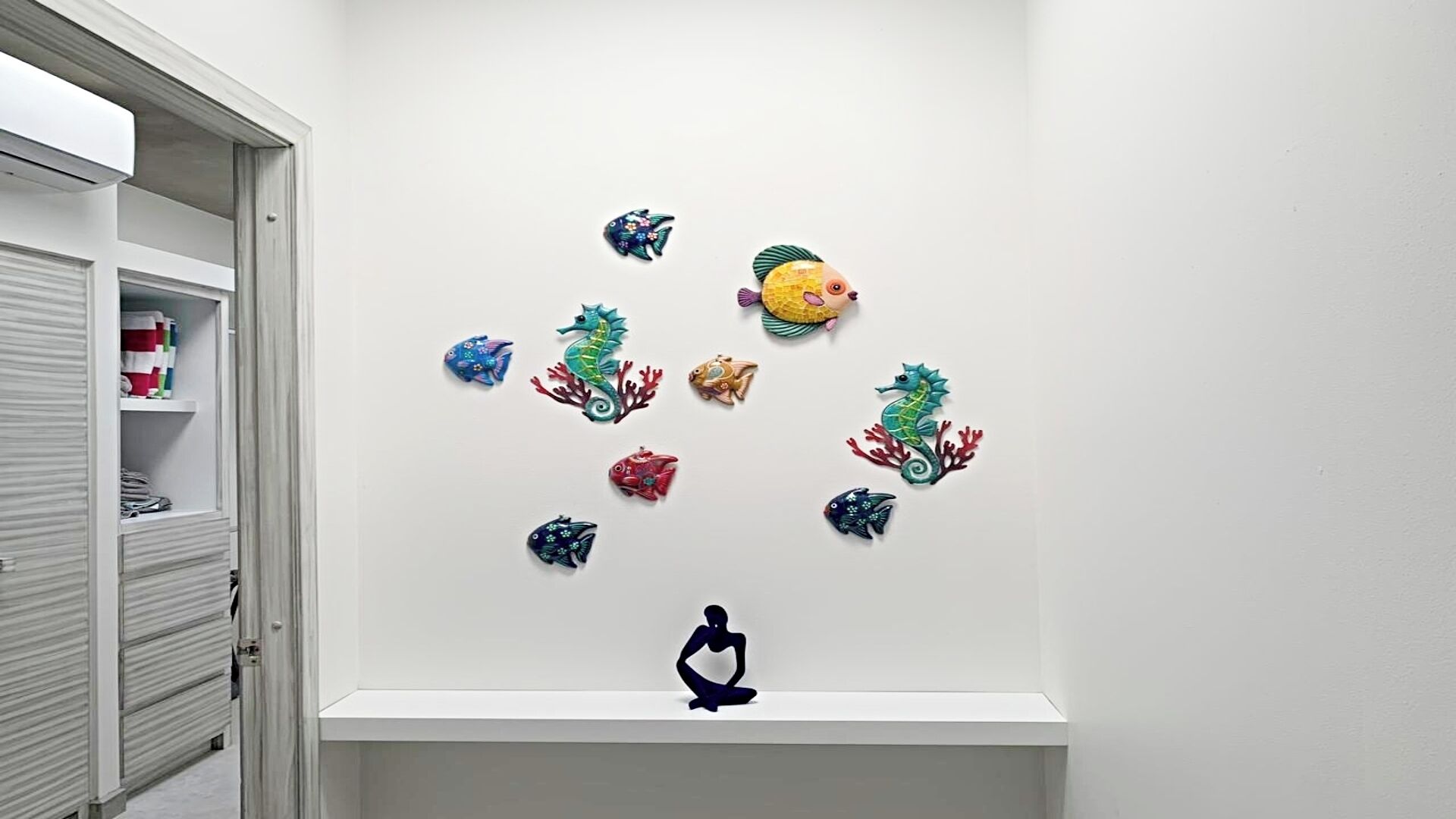 Una pared blanca decorada con varios peces y caballitos de mar de colores.