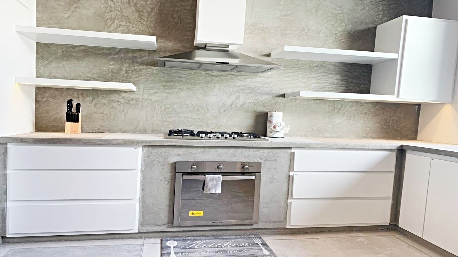 A modern kitchen with a built-in gas stove, oven, and white cabinetry.