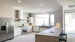 Una cocina moderna con refrigerador de acero inoxidable, horno empotrado y una isla grande con taburetes de bar.