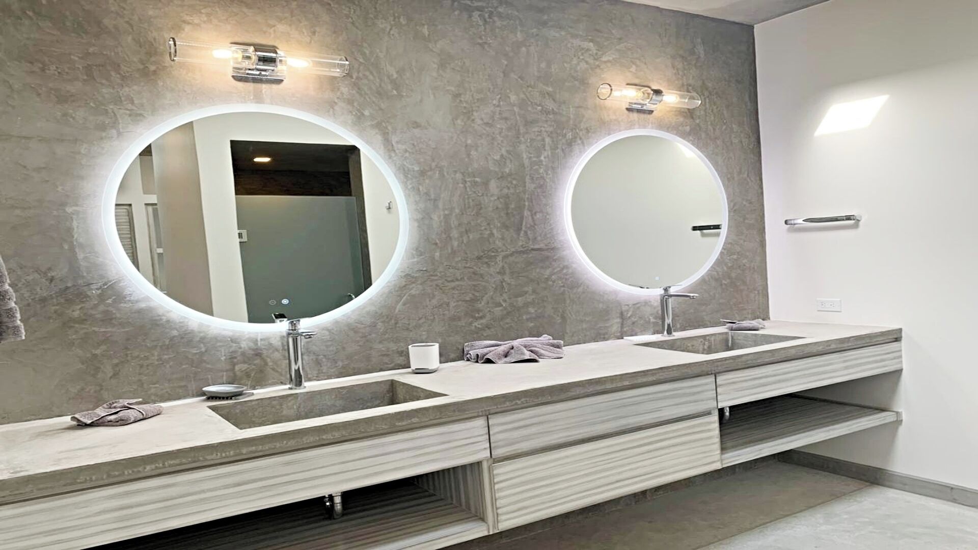 A modern bathroom with a long vanity, two round mirrors, and a single sink.
