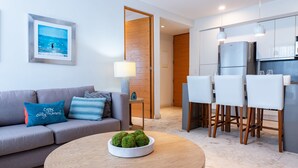 A modern living room with a grey sofa, a round wooden coffee table, and a dining area with white chairs and a kitchen in the background. - Brand New Penthouse at Anah with 2 bedrooms and private roof top terrace! (Solidaridad)