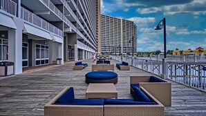 A waterfront promenade with outdoor seating and a view of a high-rise building. - 5 Pools at this 1st Floor Condo with Beach Access at Laketown Wharf 119 (Panama City Beach)