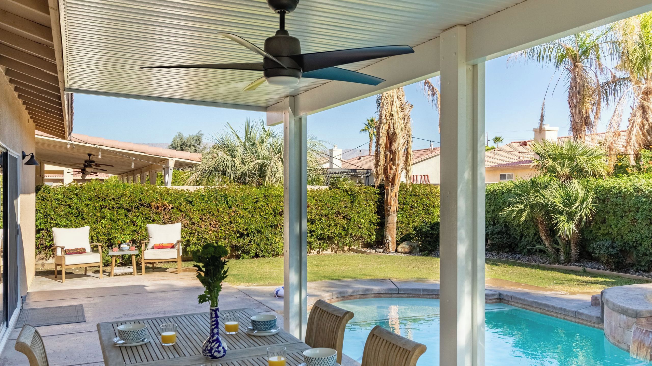 A covered outdoor patio with a pool, seating, and a view of the surrounding landscape.