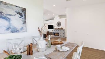 A dining area with a table set for two, a fireplace, and a mounted TV.