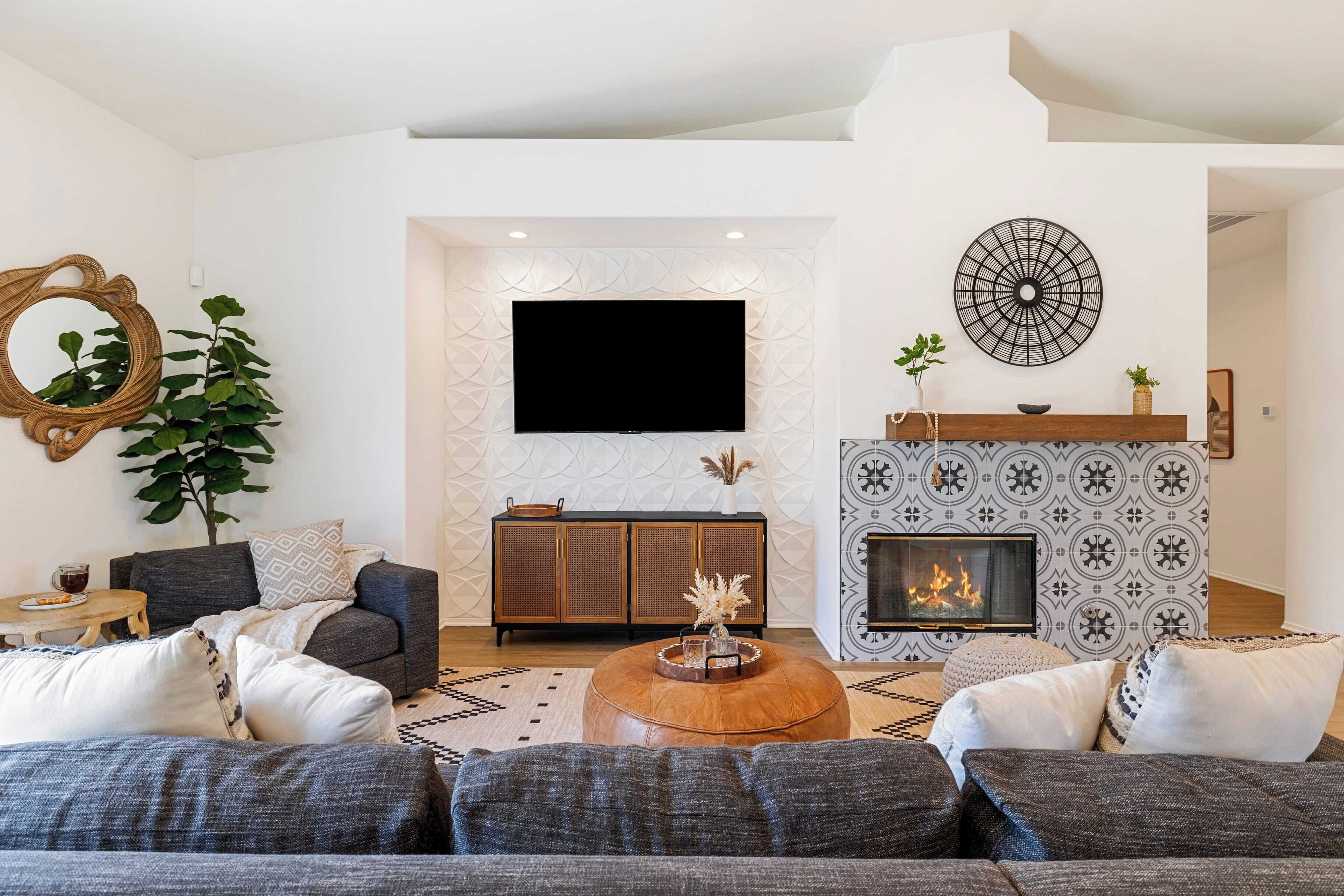 Ein modernes Wohnzimmer mit einer Sofagarnitur, einem Couchtisch, einem Kamin und einem flachbildfernseher an der Wand.