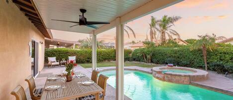 A covered outdoor area with a pool, seating, and a ceiling fan.