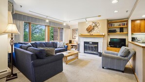 Un salon avec une cheminée, un canapé, un fauteuil et un téléviseur.
