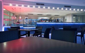 Un restaurante moderno con una zona de bar, asientos y una vitrina con botellas.