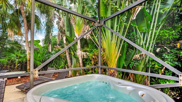 A hot tub surrounded by metal beams and lush tropical vegetation.