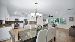 A modern kitchen with white cabinets, stainless steel appliances, and a dining area with a glass table and white chairs.