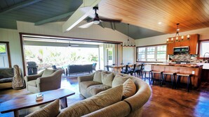 Un salón espacioso con un sofá curvo, una mesa de comedor y una zona de cocina con barra.