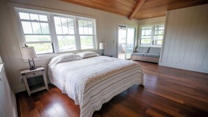 Un dormitorio con una cama grande, suelo de madera y vistas a un balcón.