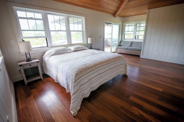 Un dormitorio con una cama grande, suelo de madera y vistas a un balcón.