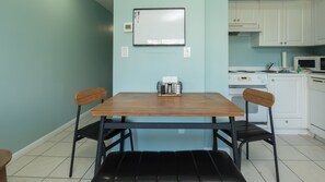 En matplats med ett träbord och två stolar, en whiteboard på väggen och ett kök i bakgrunden.