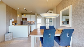 Une cuisine moderne avec des meubles blancs, un îlot central et des luminaires suspendus.