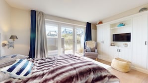 Ein Schlafzimmer mit einem Bett, einem Sessel, einem Kleiderschrank und einem Fernseher.