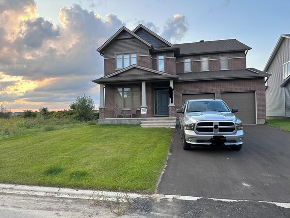 A two-story house with a driveway and a parked truck. - Bed & Stay (Russell)