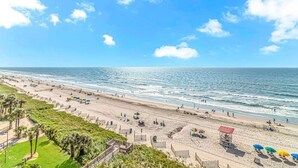 Ein Strand mit blauem Himmel, sandigem Ufer und einem Rettungsschwimmerstand.