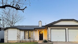 A two-story house with a garage, a front door with a light, and a small front yard. - Office, Patio, Yard, Pet Friendly, Playground (Austin)