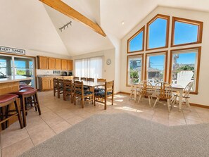 Un'ampia cucina con mobili in legno, un'area pranzo con sedie e grandi finestre con vista.