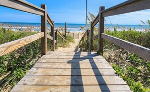 A wooden boardwalk leading to a beach with a clear view of the ocean.