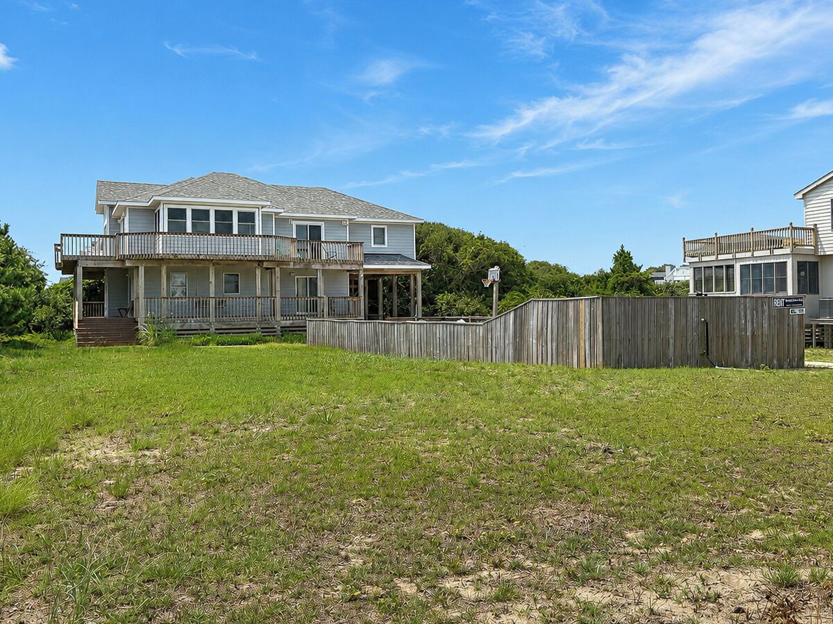 A two-story house with a covered porch and a fenced backyard.