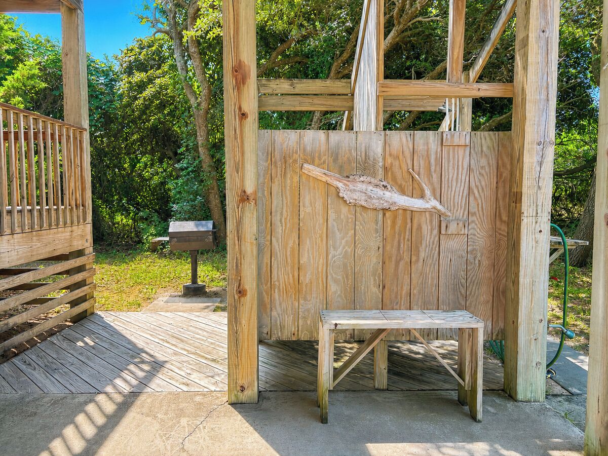 Une structure en bois comprenant un banc et une table, le tout entouré d’arbres.