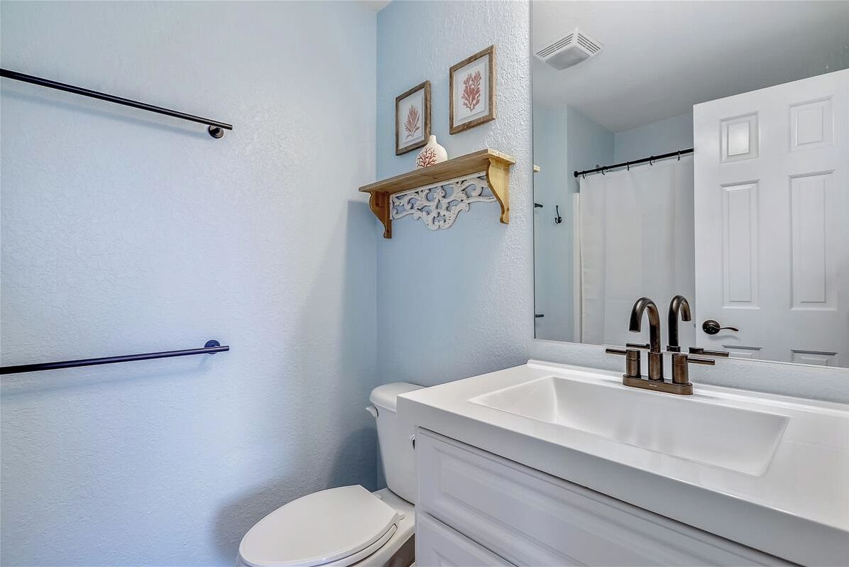 A bathroom with a white sink, a toilet, and a towel rack.