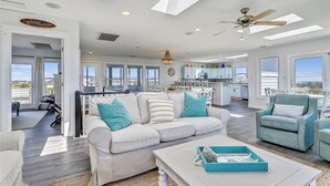 A spacious living area with a white sofa, teal armchairs, and a coffee table. A ceiling fan and pendant light are visible. - ENDLESS SUMMER 2 is the ideal location with Private Pool (Southern Shores)