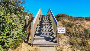 A wooden staircase leading up to a sign that reads "KEEP OFF THE DUNES."