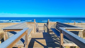 A wooden boardwalk leading to the beach with a clear view of the ocean.