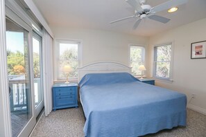 A bedroom with a bed, two nightstands, a ceiling fan, and large windows. - Lazy Days - Enjoy beautiful sunsets from this soundside home w/Private Pool! (Southern Shores)