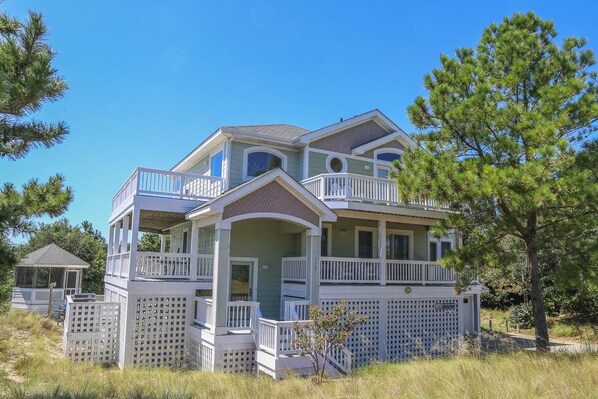 A two-story house with a balcony, a covered porch, and a fenced yard. - Lazy Days - Enjoy beautiful sunsets from this soundside home w/Private Pool! (Southern Shores)