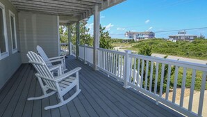 A wooden porch with white railings and two rocking chairs. - Sea & Ease - Enjoy superb ocean views and great beach access from this home w/Private Pool! (Southern Shores)